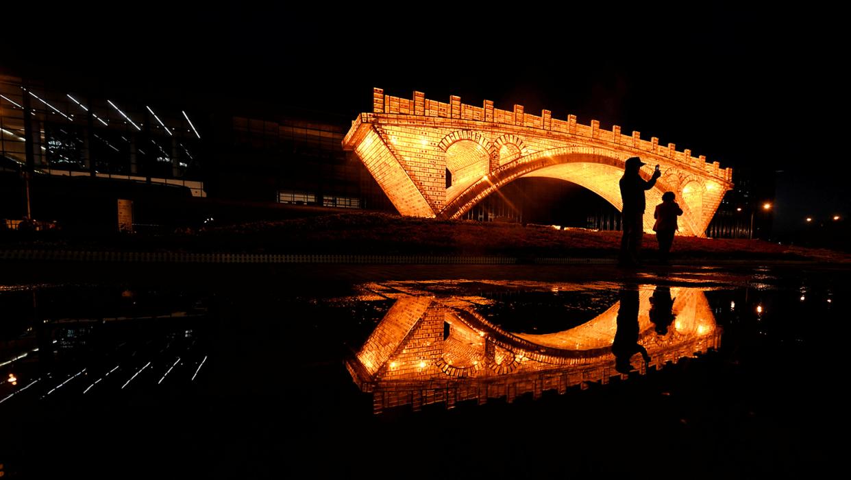 People take pictures in front of a "Golden Bridge on Silk Road" installation, set up ahead of the Belt and Road Forum, outside the National Convention Centre in Beijing, China May 11, 2017. Picture taken May 11, 2017.