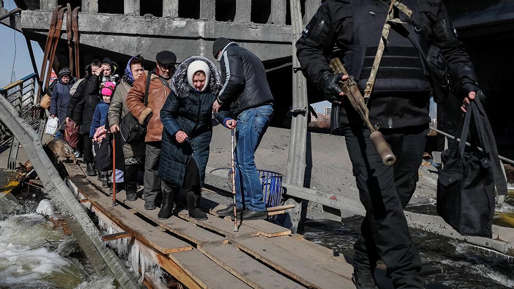 People cross the Irpin river near a destroyed bridge as they evacuate from Irpin town, amid Russia's invasion of Ukraine, outside of Kyiv, Ukraine March 12, 2022.